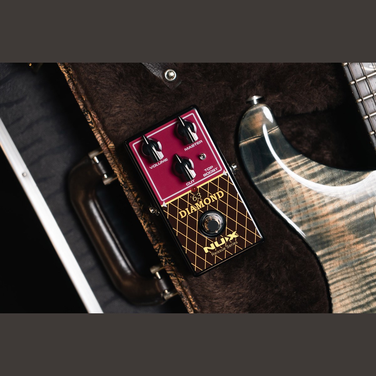 Phơ Overdrive NUX '63 Diamond NRO-6 – '63 Diamond đặt cạnh cây guitar điện trong hộp đàn