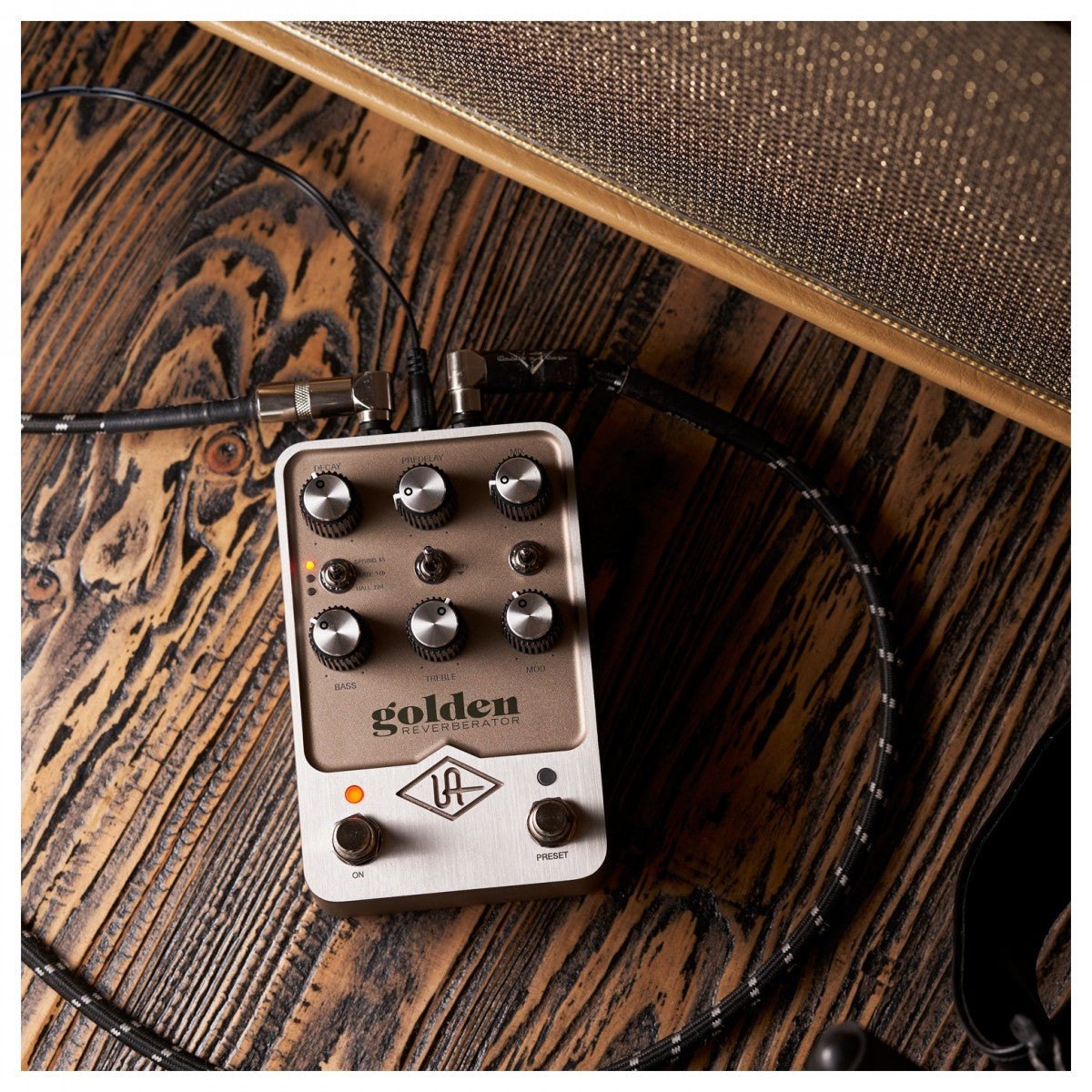 Phơ Reverb Universal Audio UAFX Golden Reverberator – đặt trên sàn gỗ cạnh ampli guitar, đã cắm dây tín hiệu